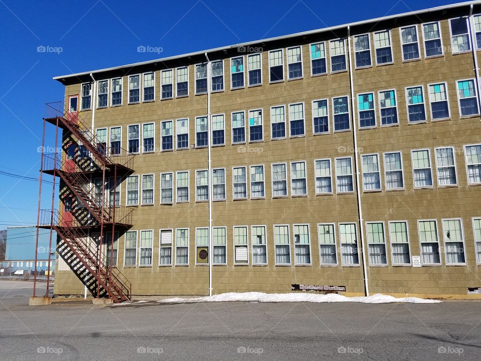 Old closed shoe factory, steel rusted fire escapes still attached, lots of floors & windows.