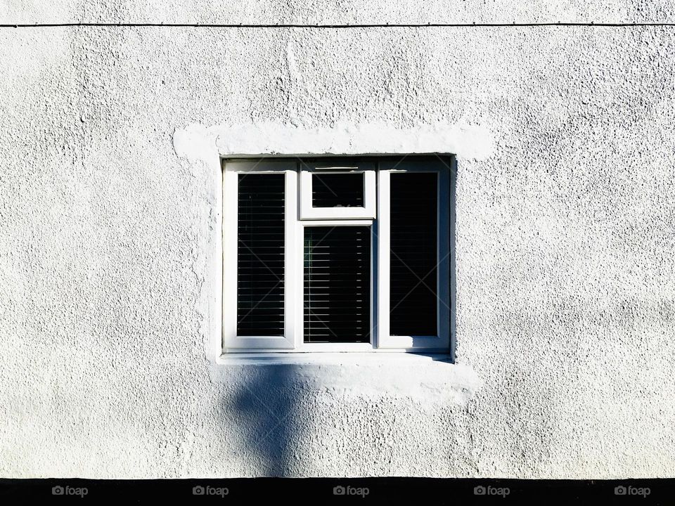 Lonely window on a white wall texture background 