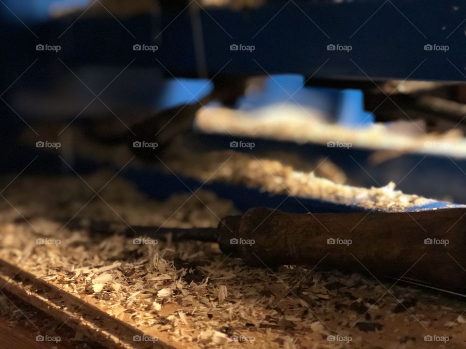 Tool lying over wood pieces under a spinning machine.