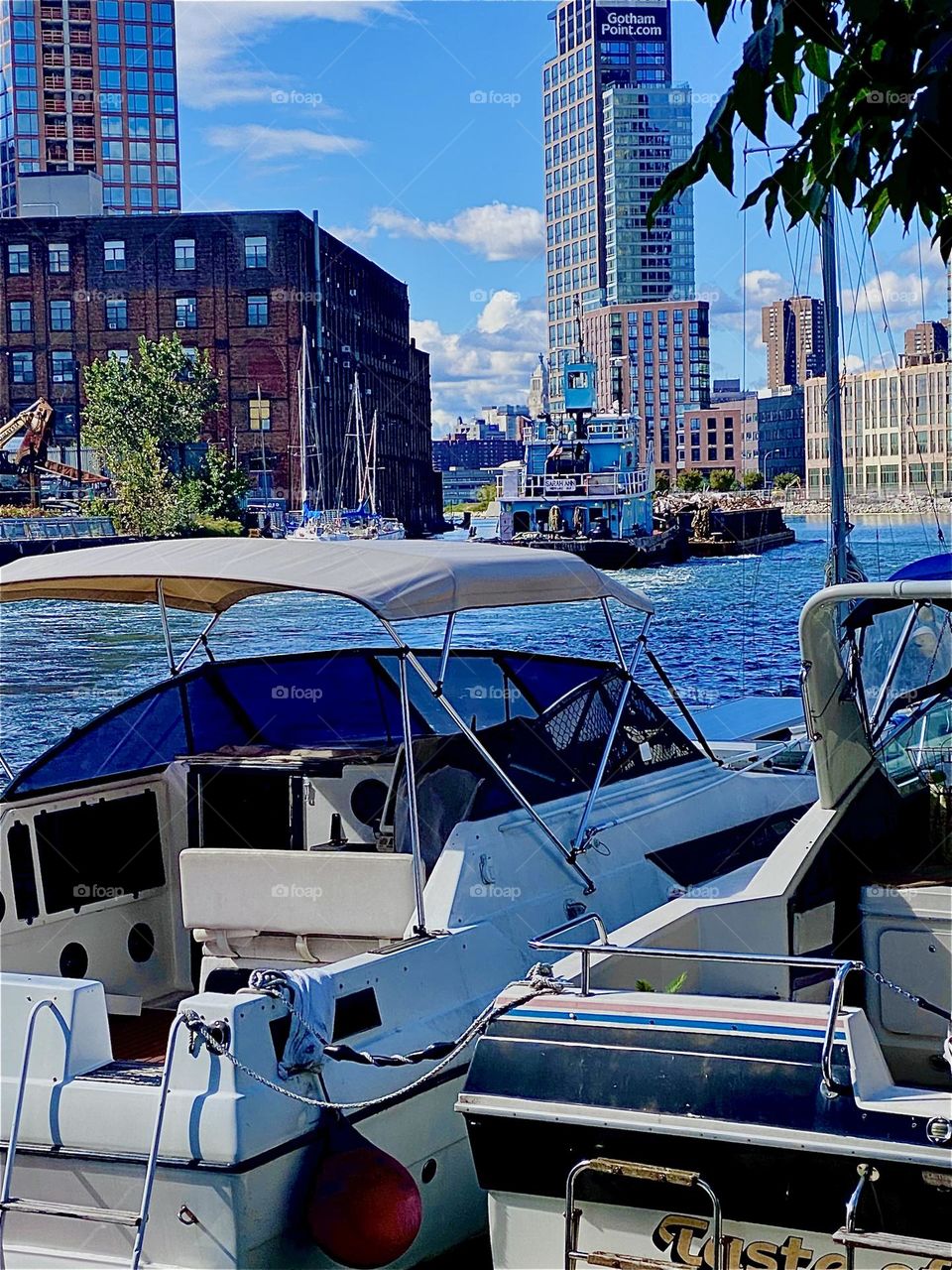 A large industrial barge is slowly moving away from us on the shore at „Newtown Creek“ by the „Pulaski Bridge“ in LIC, Queens on a bright sunshiny day in October 2023. Hypnotic Productions