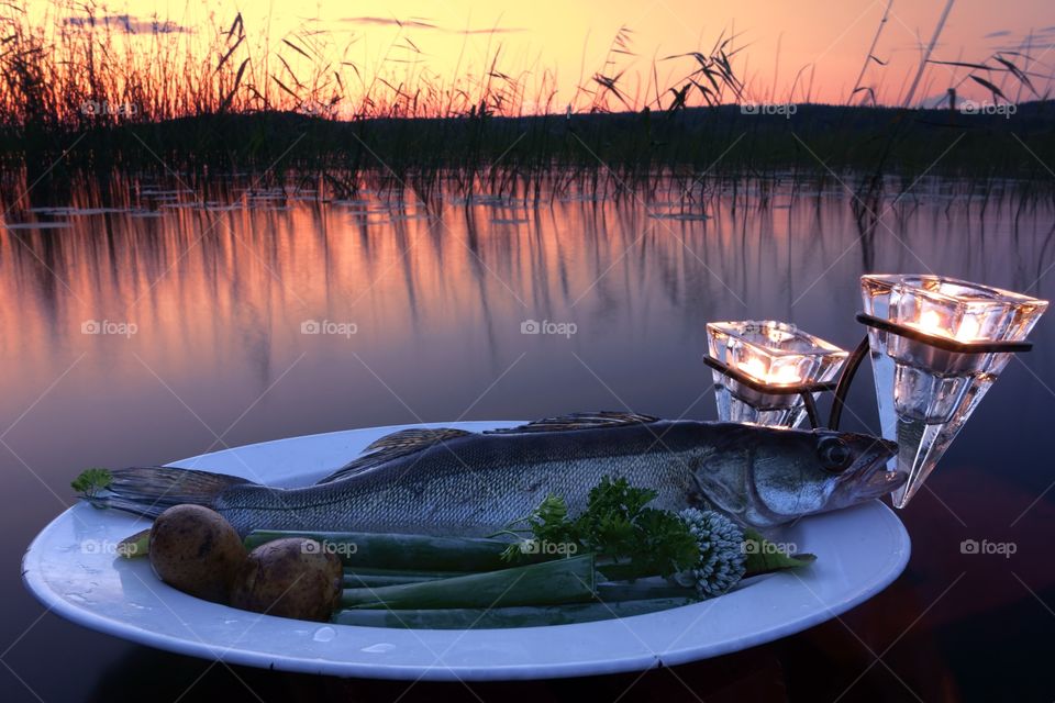 Fresh fish catch on a plate. Fresh fish catch (pike perch) on plate served with fresh vegetables in outdoors setting on a lake