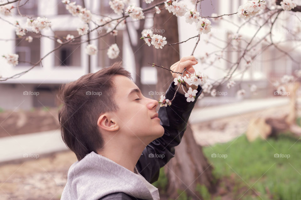 Portrait of teenager and spring flowered branches of tree.