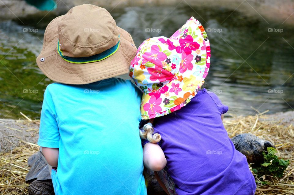 Young brother and sister sitting together outdoors