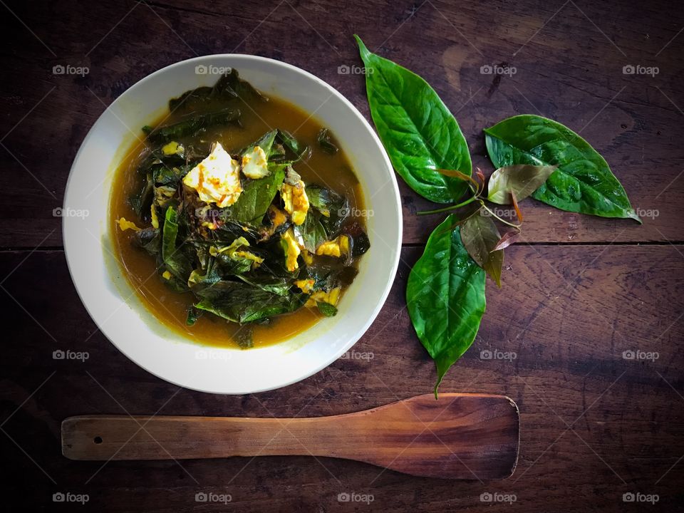 Gnetum gnemon or melinjo leaves and fish in yellow hot and sour soup