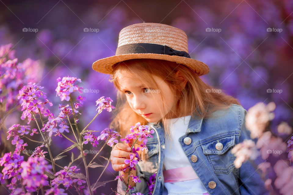 Cute little girl portrait in blossom meadow at sunset 