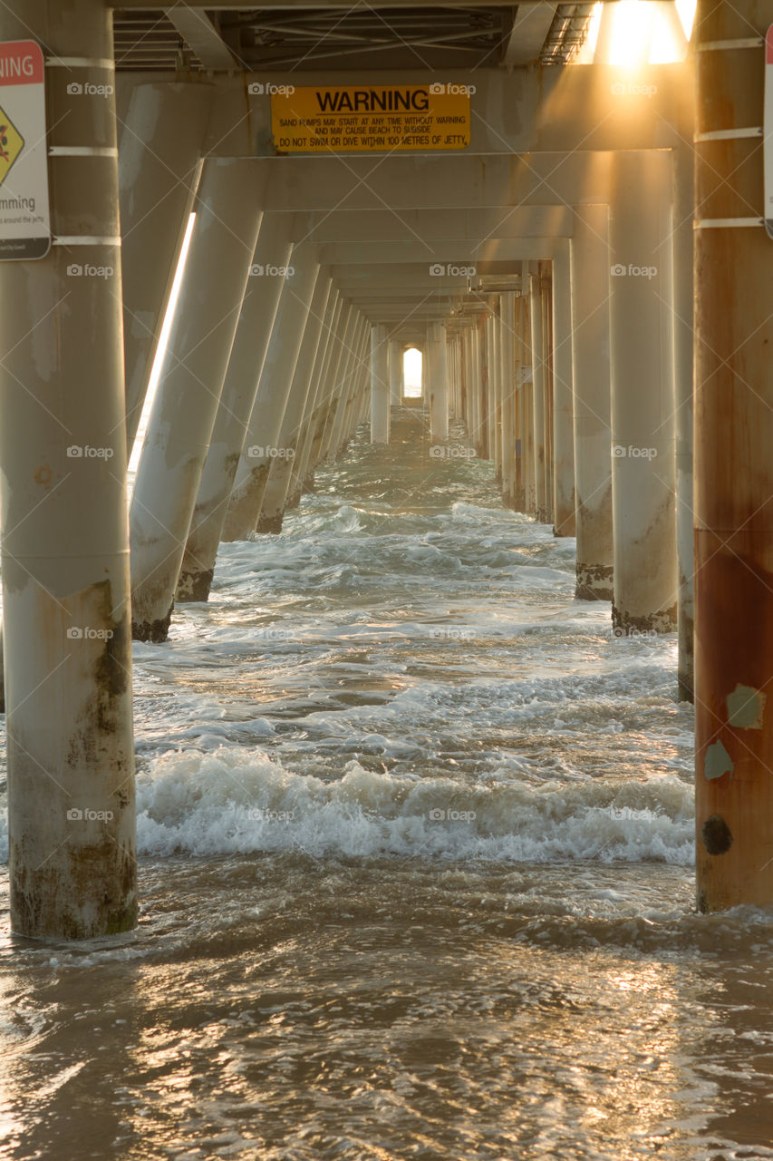 Sea surf and concrete columns of pier