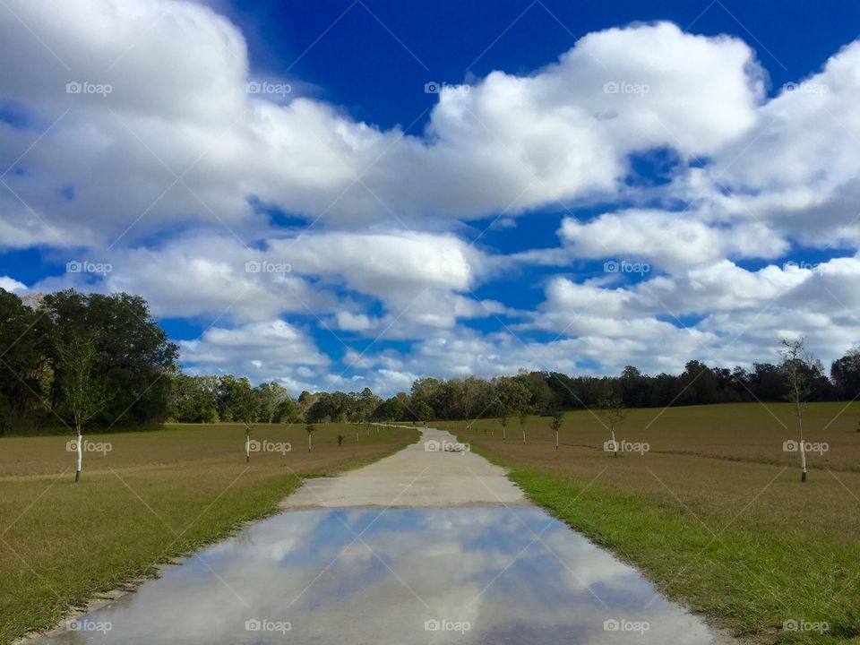Blue sky and clouds reflection in puddle