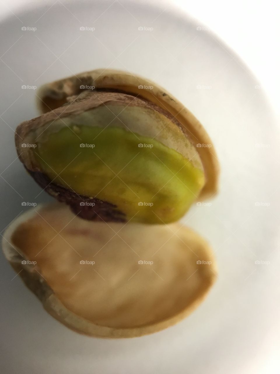 Single pistachio nut with its shell. Close up on the green nut. 