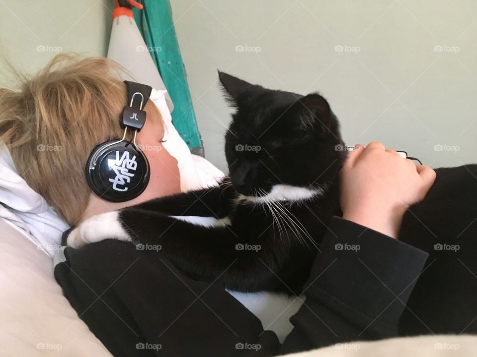 Black cat resting with boy in headphones 