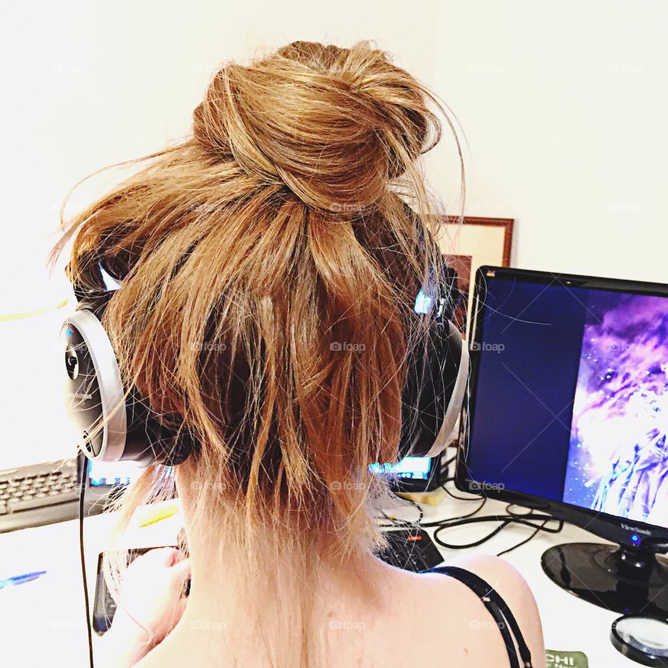 A girl with a Messy hair bun and listening to music with her headphone