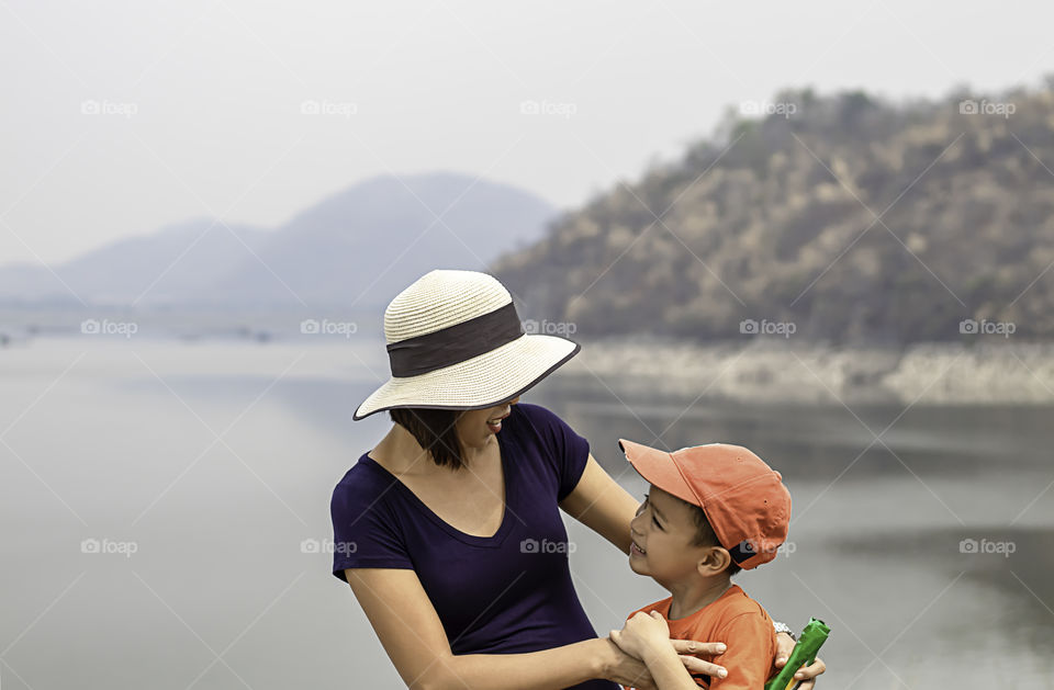 Portrait of mother and son are smiling Background mountains and water at Krasiew dam ,Supanburi Thailand