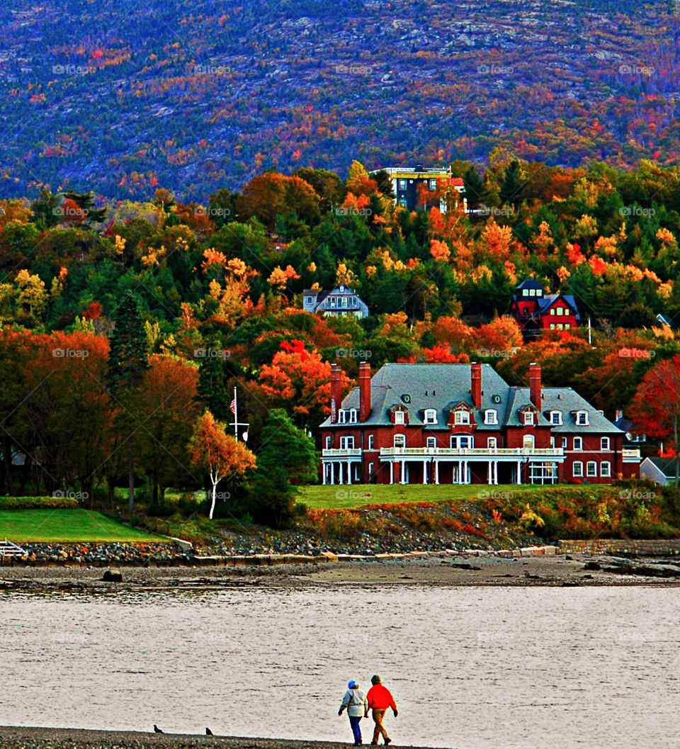 A couple walks the coastline during autumn. Crisp beach walks; apple orchards; and brilliant crimson, gold and orange foliage are just a few of the things that make fall in Maine a glorious time to visit