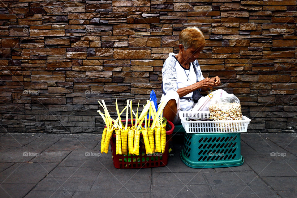 street vendor sells Suman or steamed glutenous rice wrapped in palm leaves