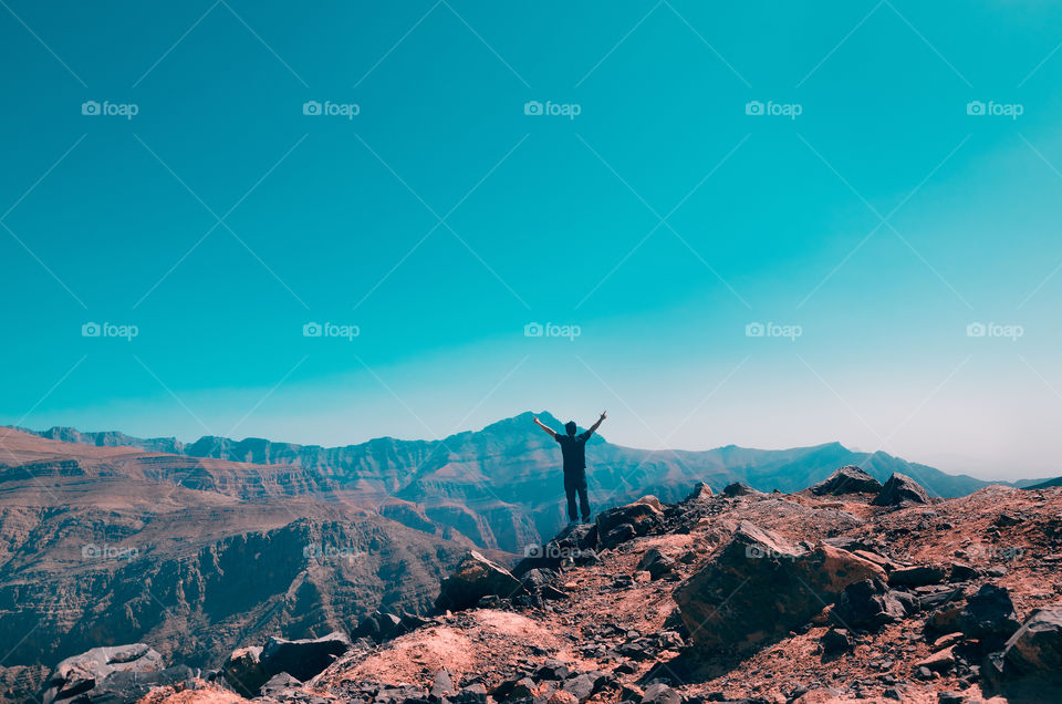 A hiker raised his hands as a sign of success and fulfillment.