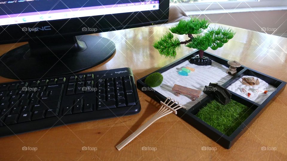 Sparkly desk with large black monitor, keyboard and marching black zen garden