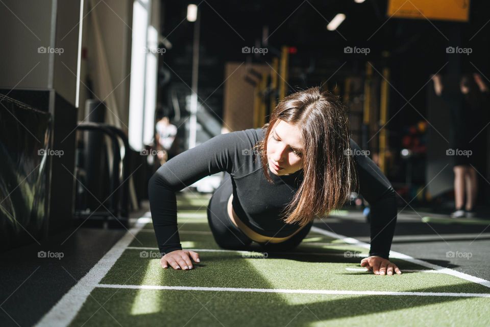 Young brunette woman training her muscles in the fitness club gym