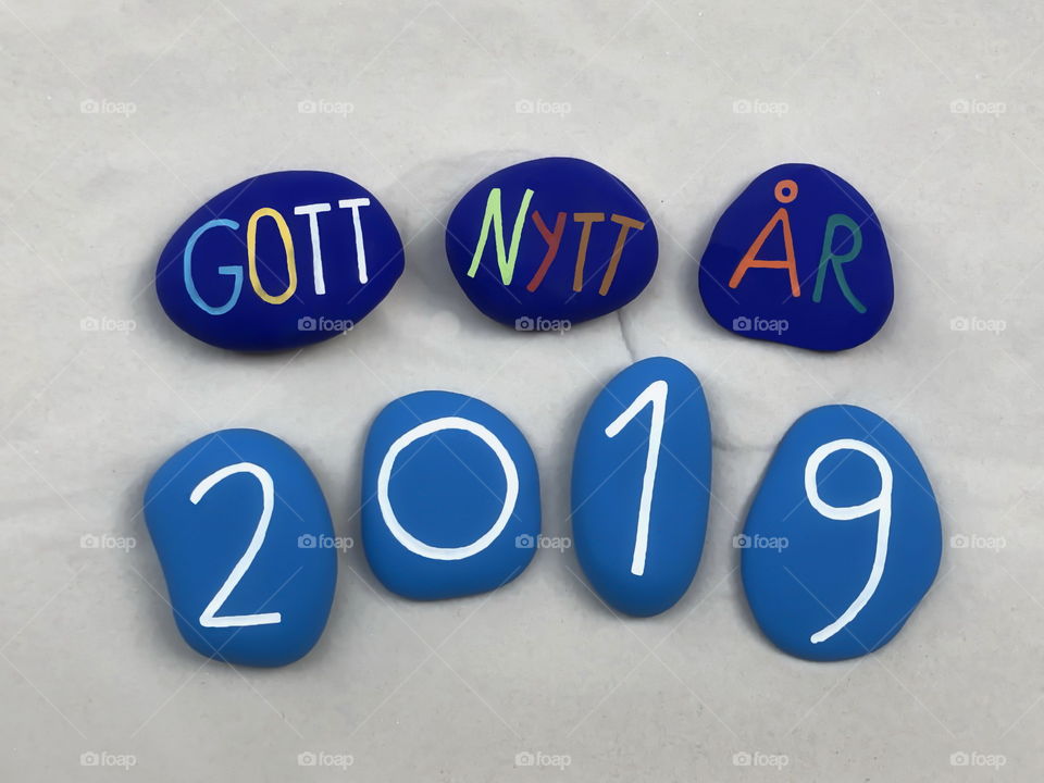 Gott nytt år 2019, swedish Happy New Year 2019 with colored stones over white sand