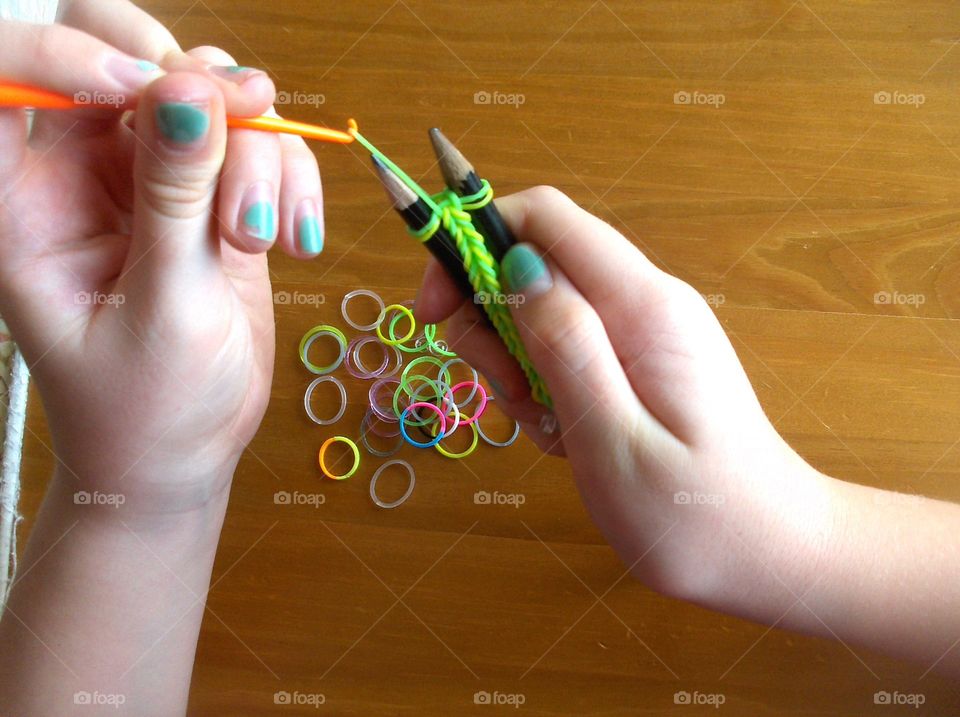 girl's hands making bracelet from rubber rings