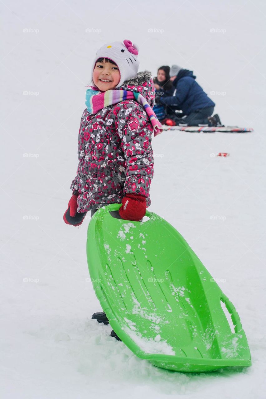 Happy cute little girl is having fun sliding from a hill