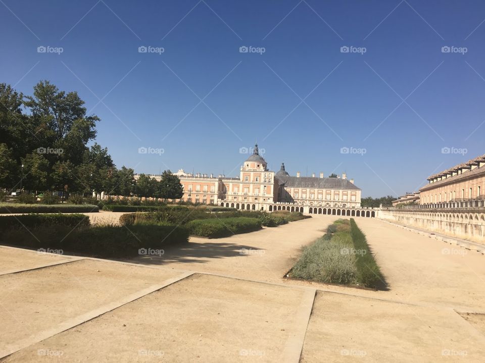 Beautiful landscape of the Grand Palace in Aranjuez, Spain. The view of the land against the neutral red brick colors palace and the green gardens make for a calm and peaceful environment.