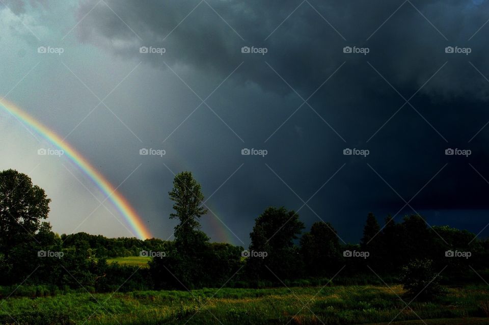Rainbow and thunderstorm over lush field