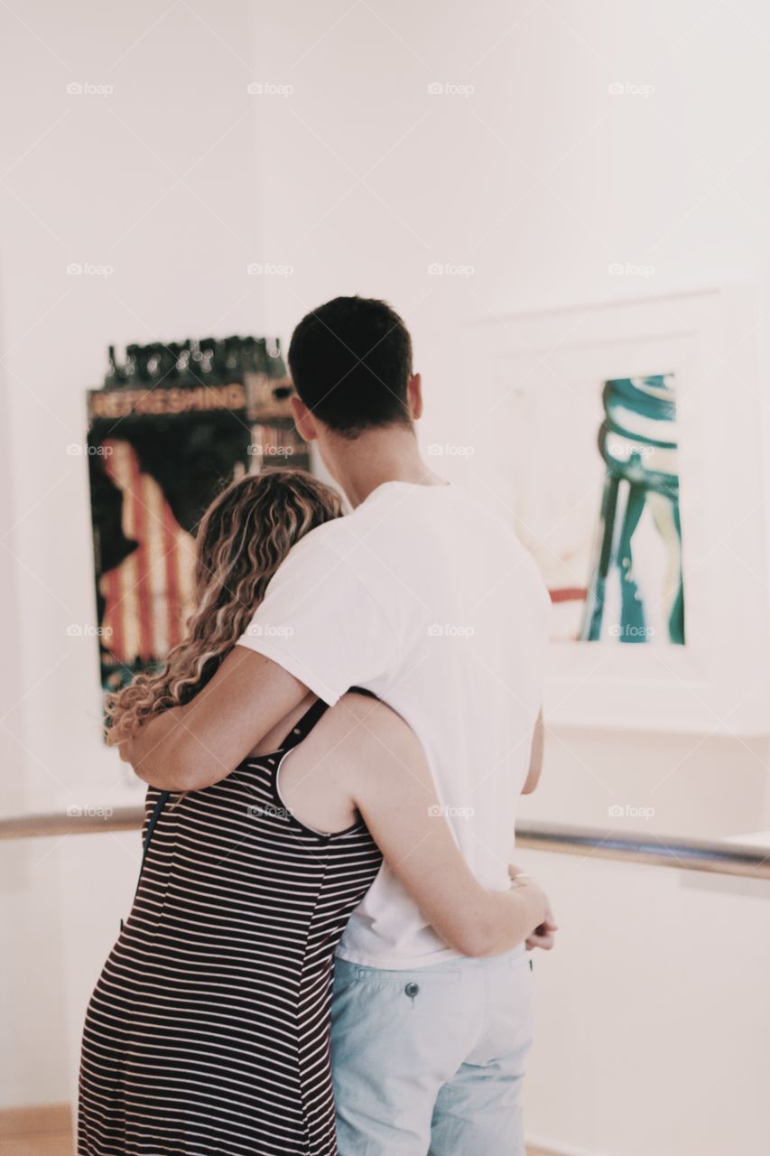 Young couple in love watching artwork at museum exhibit 