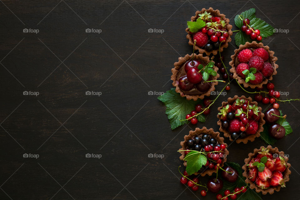 Homemade chocolate mini tarts on dark wooden background