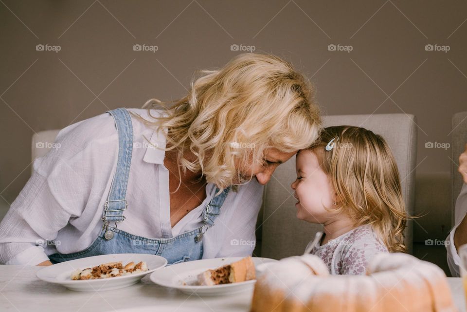 Grandma and her little girl. Cute family moment, dining at home.
