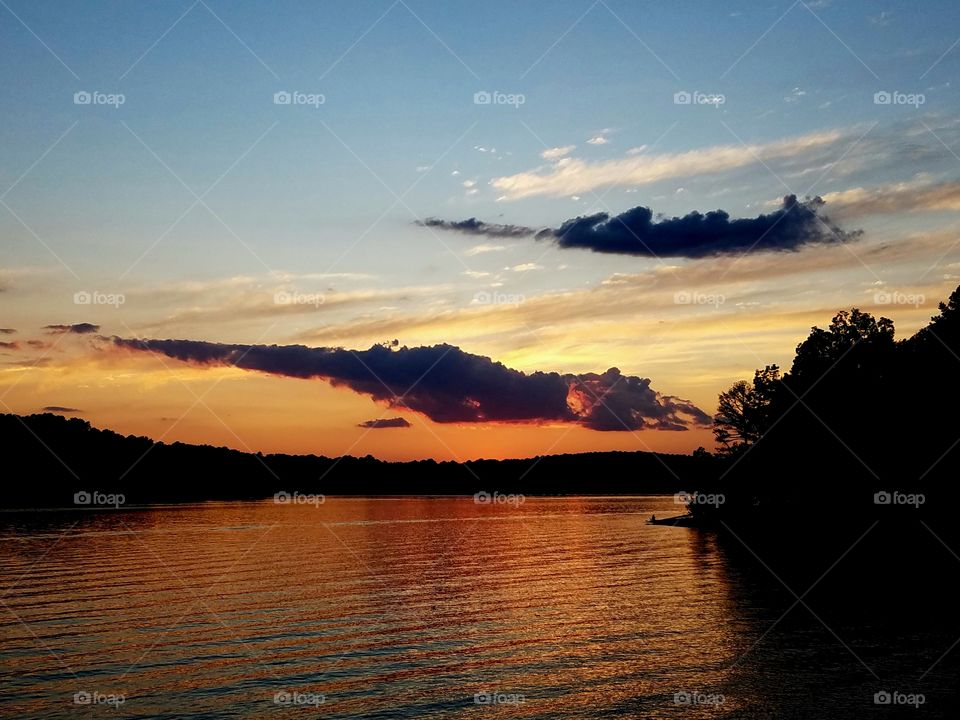 sunset over lake.  shadowed clouds.