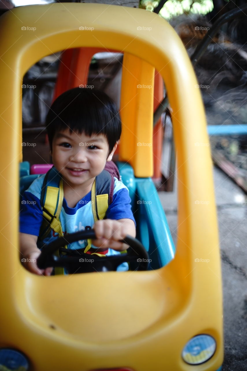 Asian boy having fun in a toy cart