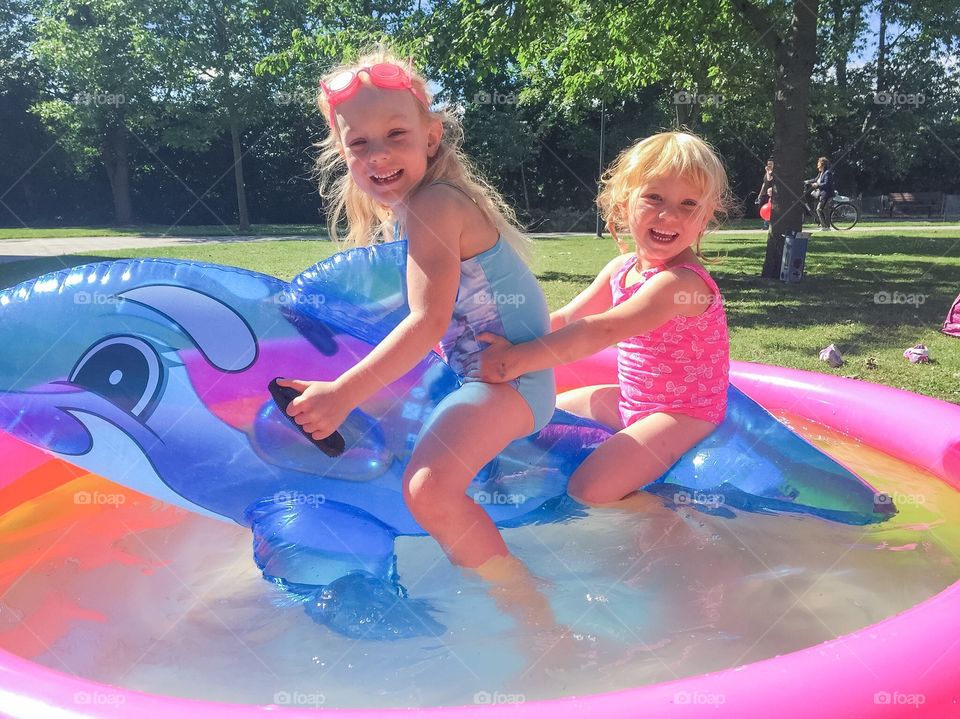 Two sisters playing in a minipool in the summer in Malmö Sweden.