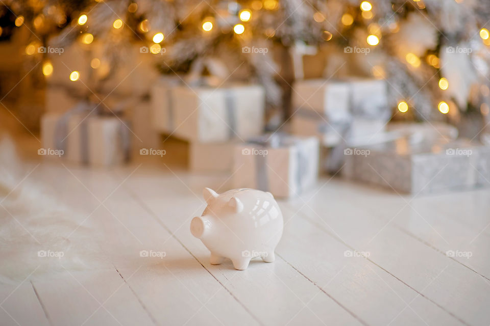 piggy bank with 100 dollars banknote in festive New Year atmosphere of scenery. Magical bokeh with Christmas tree and bright lights.