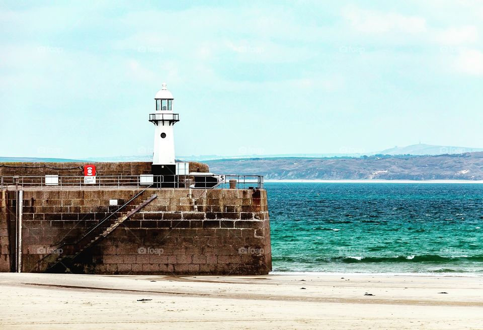 St. Ives in Cornwall with a small lighthouse on the harbour wall.