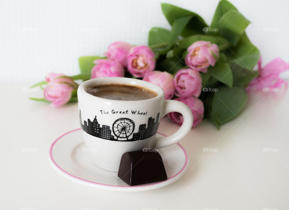 Cup of coffee, little chocolate and pink flowers