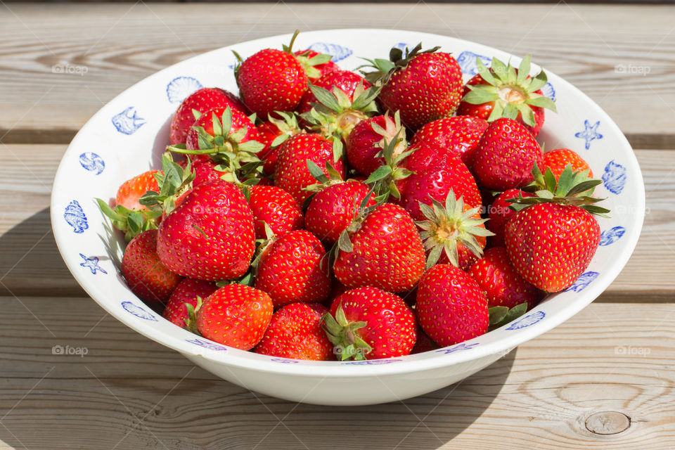 Strawberries in a white bowl in sunny weather - skål med jordgubbar en solig fin dag