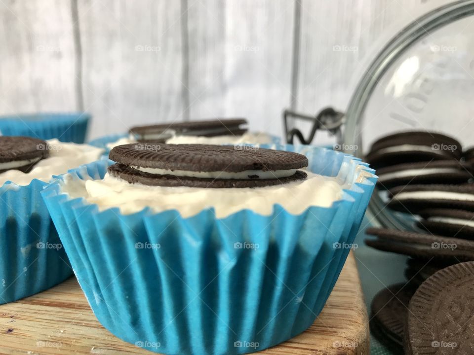 Oreo cookie ice cream cupcakes on a wooden board and white and blue background 