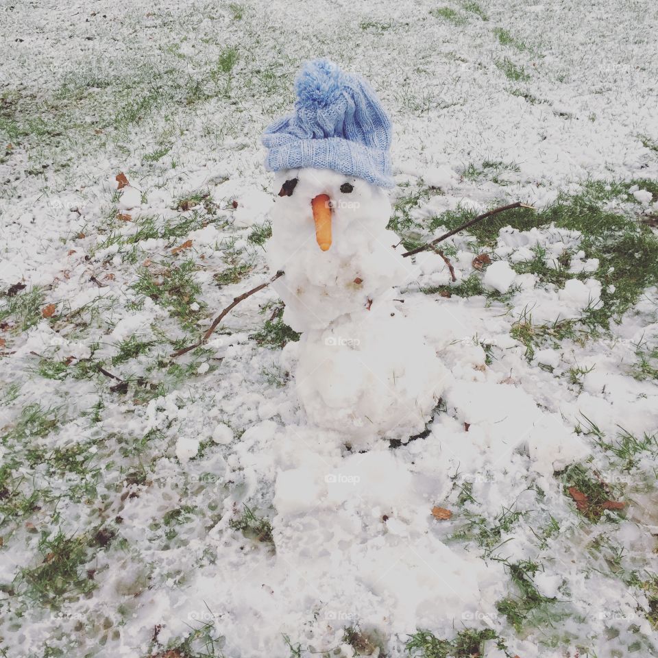 Little melting snowman in blue hat