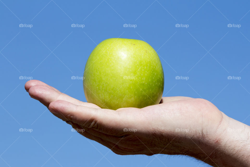 A person holding green apple