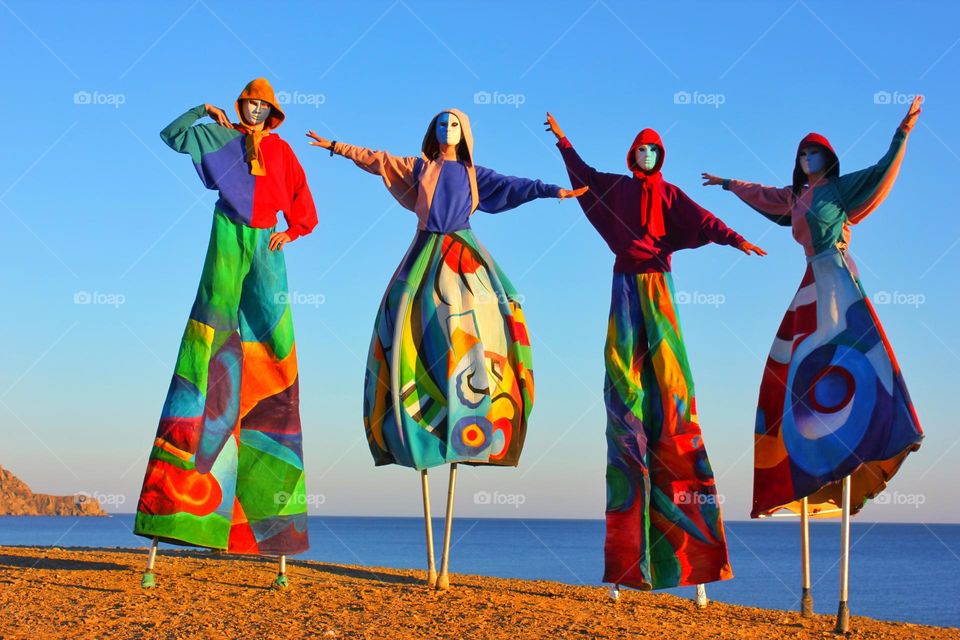 masquerade show on the seashore. people in colored costumes and masks. photo without faces.