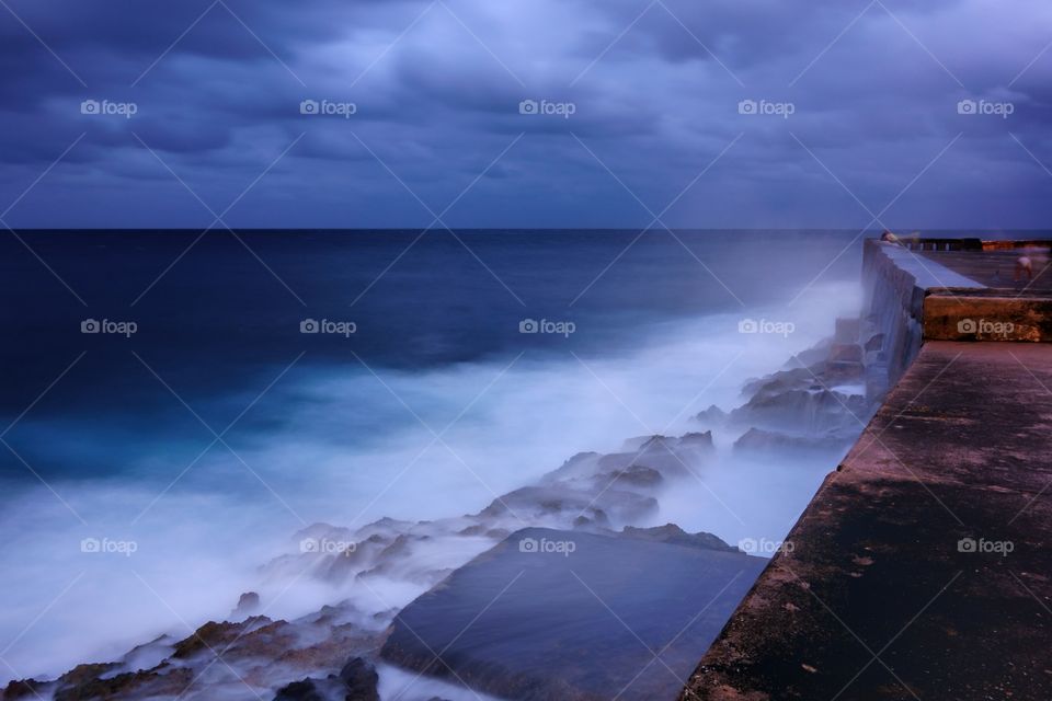 Walls of the Malecón in Havana. Evening by the walls of the Malecón esplanade in Havana, Cuba and dramatic sea bounding water on the rocks.