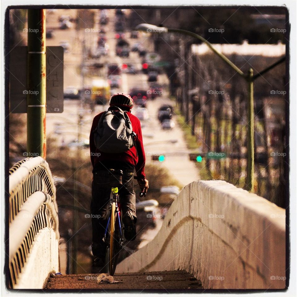 Man Biking on Bridge