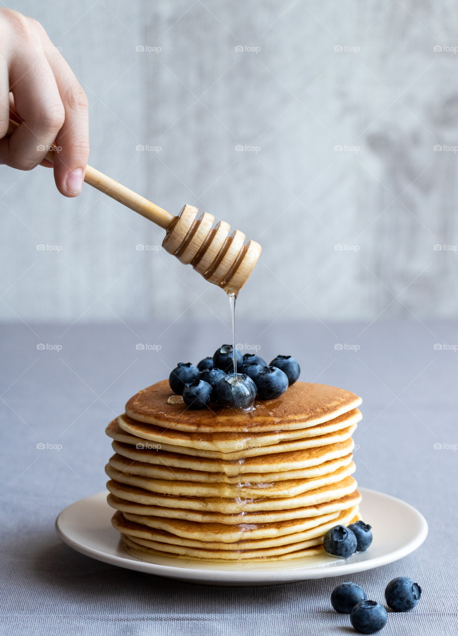 Delicious moments with handmade pancake made by almond flour served with honey and blueberries.