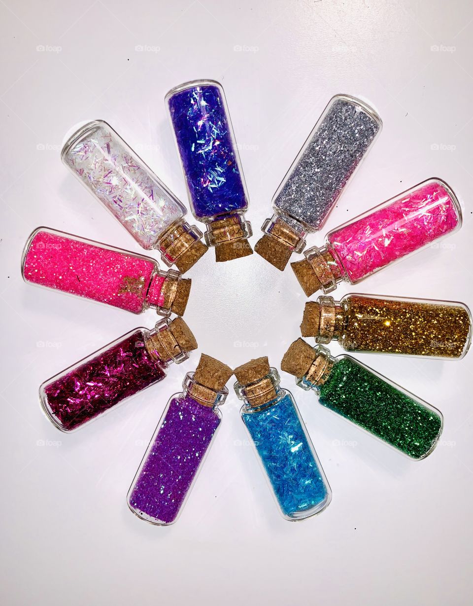 small bottles with colorful sparkles on a white background