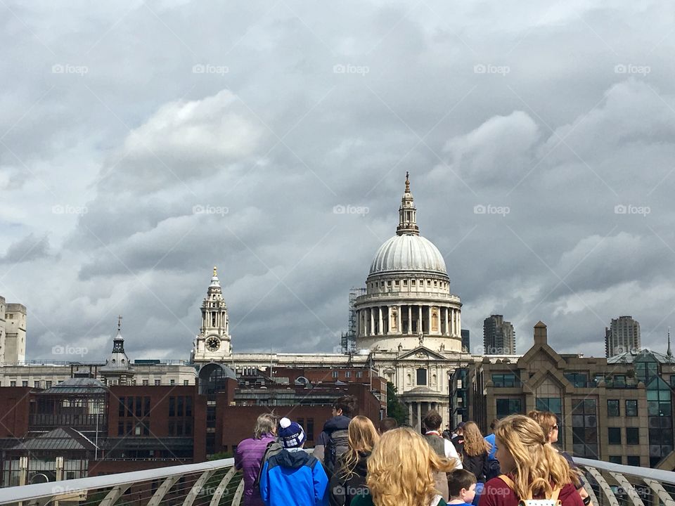 People walking on the Millenium bridge in London with a view of St. Paul’s cathedral in the distance 