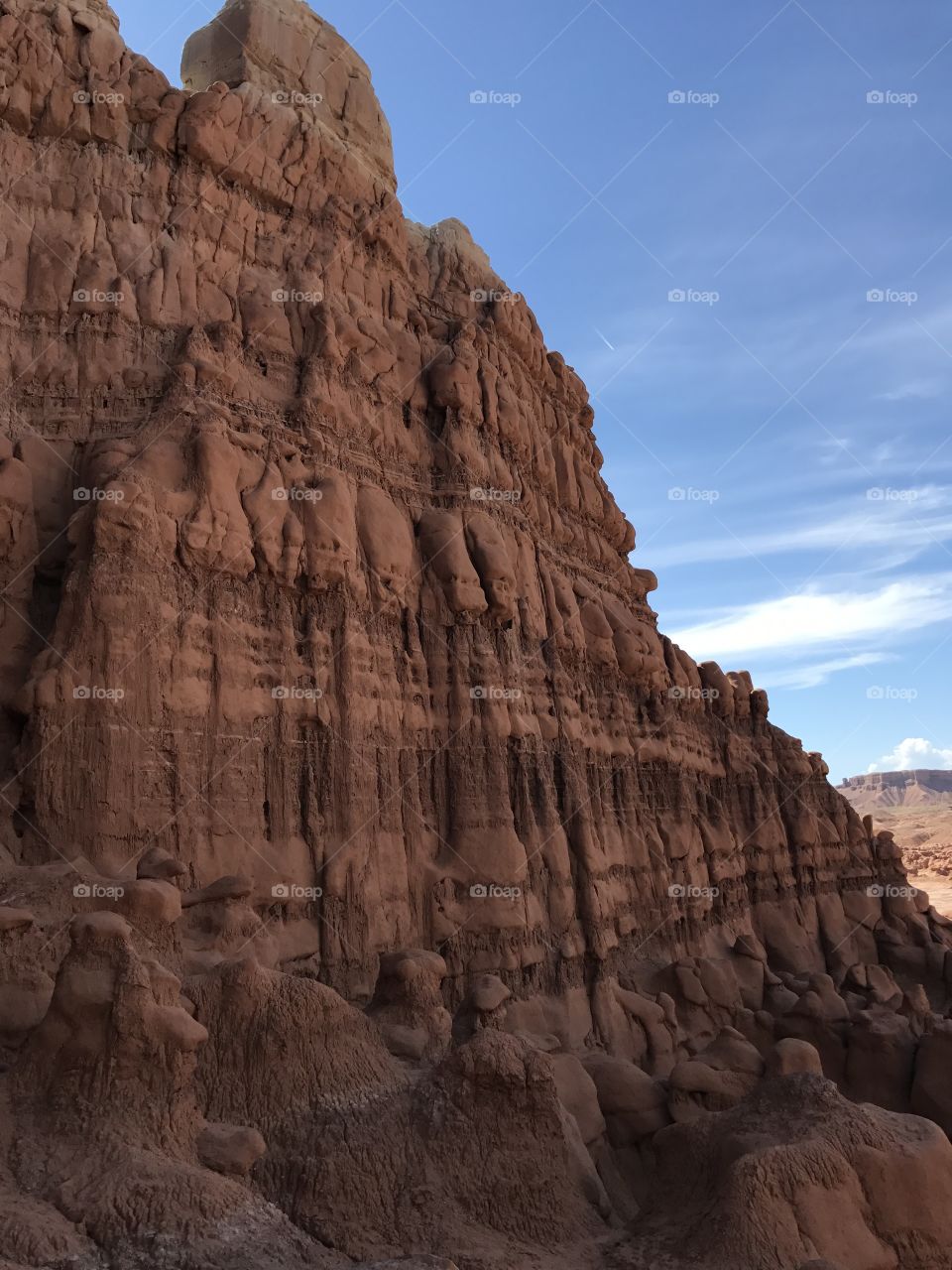 Red rock cliff face rising over Goblin Valley. 