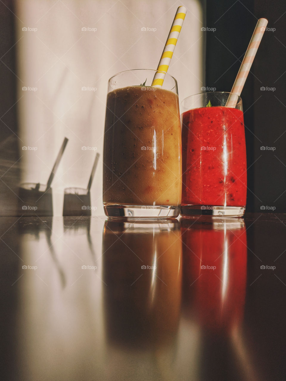 Top view of two glasses with healthy fruit smoothies with banana, berries and mint at the table.