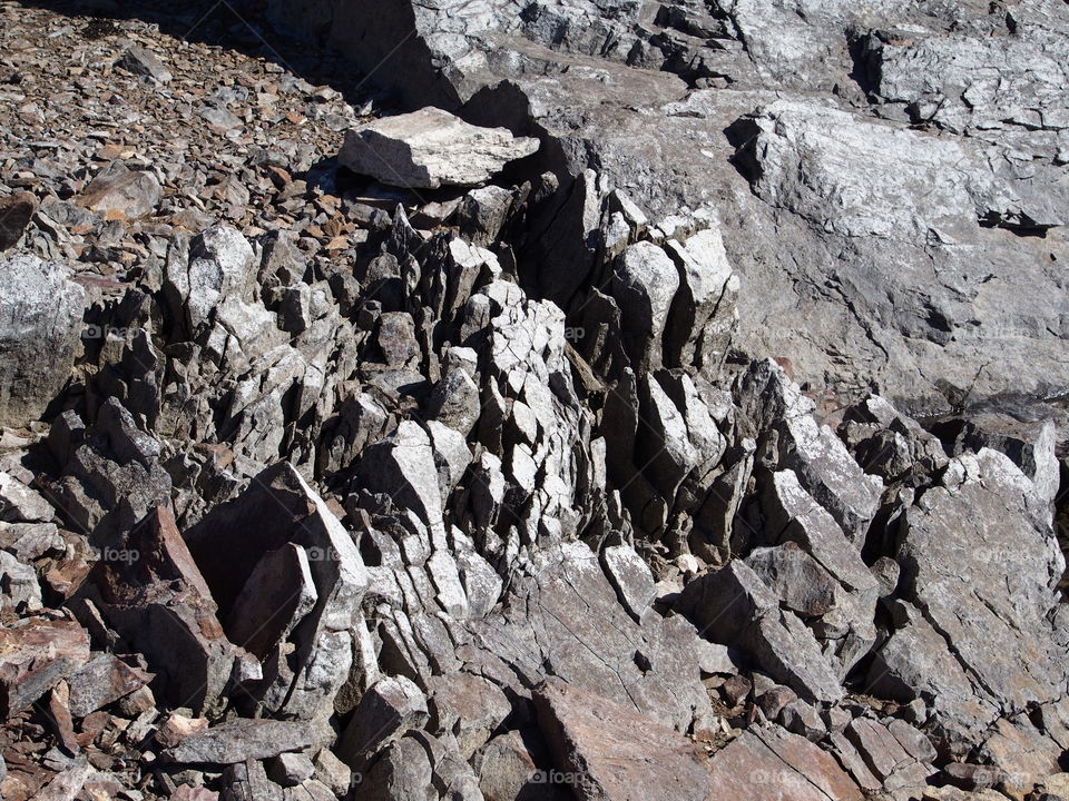 Jagged rocks and boulders along the shoreline of Ochoco Lake in Central Oregon on a sunny spring day.