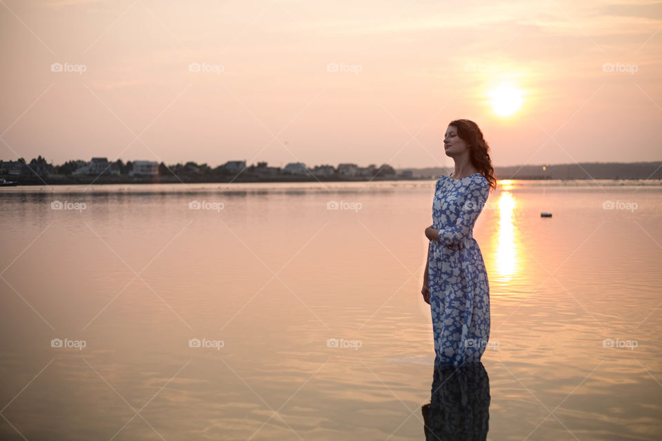 Peaceful woman standing in idyllic lake at sunset