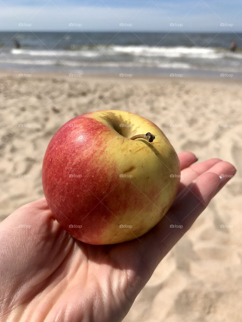 An apple on the hand and sea as a background 