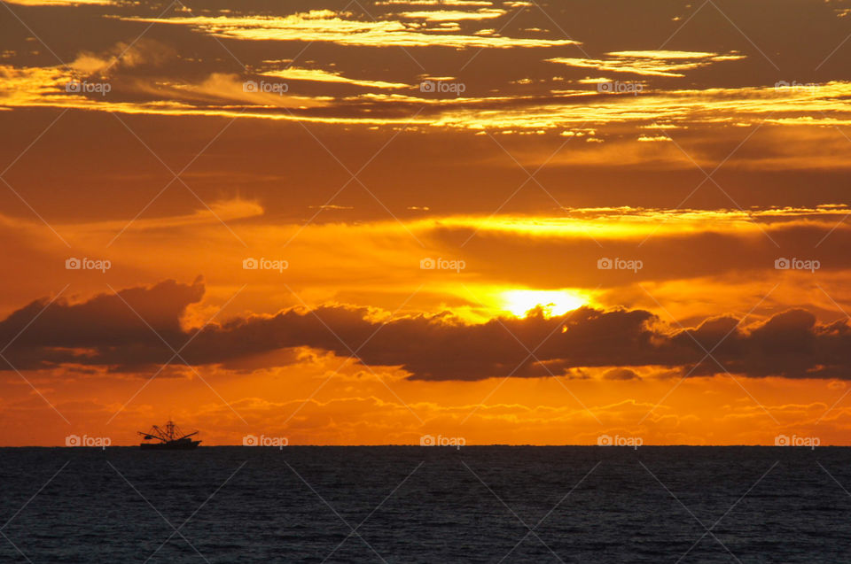 Sunrise in Daytona Beach Florida with a fishing boat on the horizon 